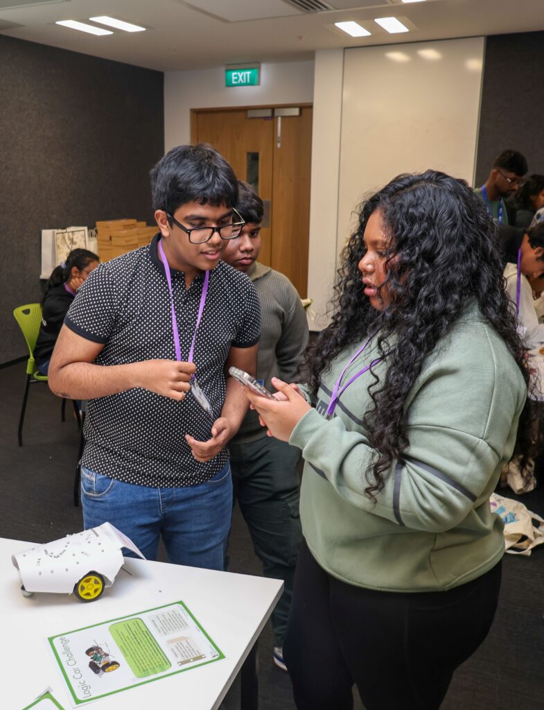 Students and instructor discussing robotics project at Little Engineers event.