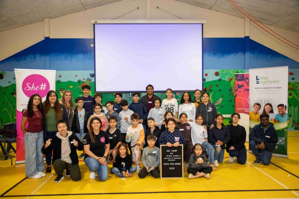 Group of children and instructors at electronics workshop in a gymnasium.