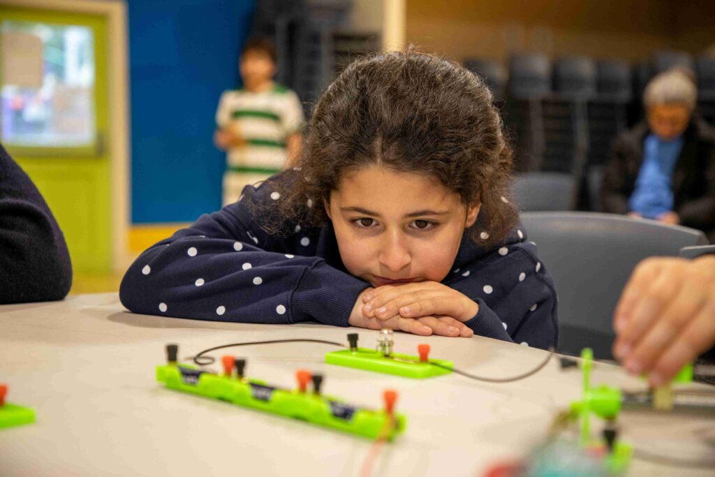 Young girl focused on electronics workshop at Little Engineers event.