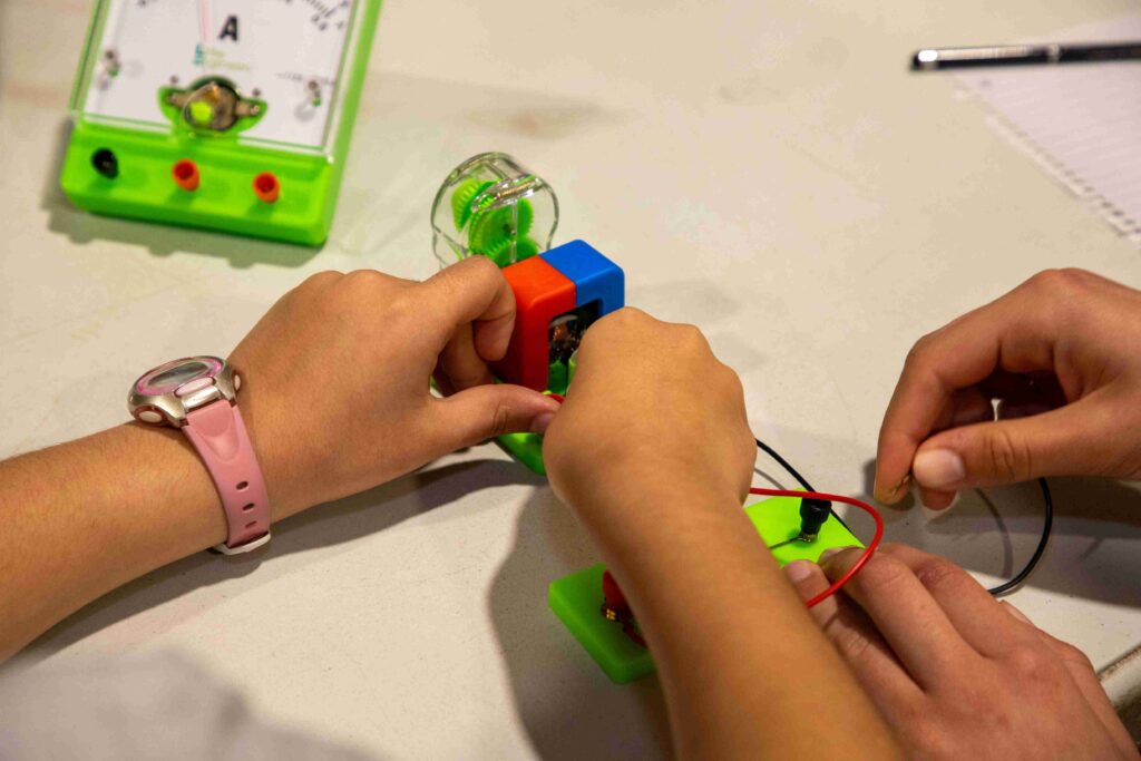 Children working on electronics project with colorful components and wires.